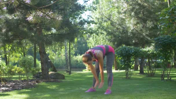 Actieve vrouwelijke doen stretching oefening op gras — Stockvideo