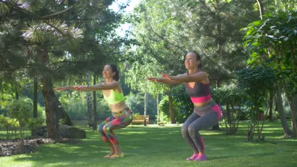 Jolies femmes sportives de fitness faisant squats dans la nature — Video