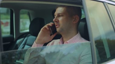 Arabanın arka koltuğunda telefonda konuşan işadamı