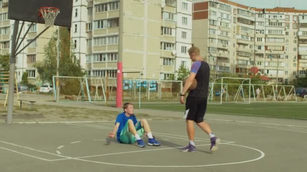 Streetball jugador ayudando a oponente caído a ponerse de pie — Vídeo de stock