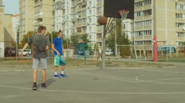 Genç streetball takım pratik top işleme becerileri ve geçen süre eğitim basketbol oyun açık sahada. Streetball oyunu sokak kortunda egzersiz basketbolcular. Ağır çekim.