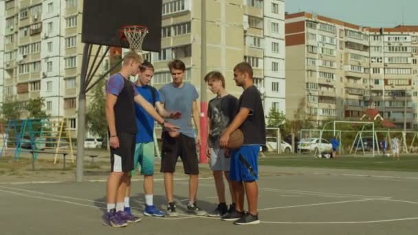 Команда баскетболистов укладывает руки на корте — стоковое видео