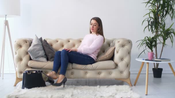 Frau ruht sich auf Sofa aus, Füße ziehen Schuhe aus — Stockvideo