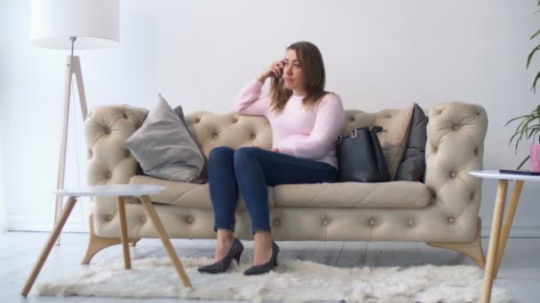 Грустная депрессивная женщина сидит на диване в гостиной — стоковое видео