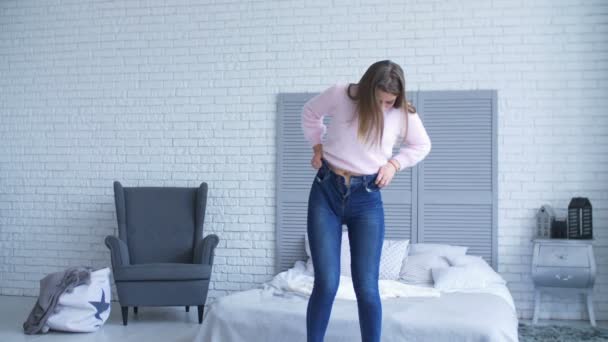 Jolie femme dans sa chambre à coucher essayant de fixer denim — Video