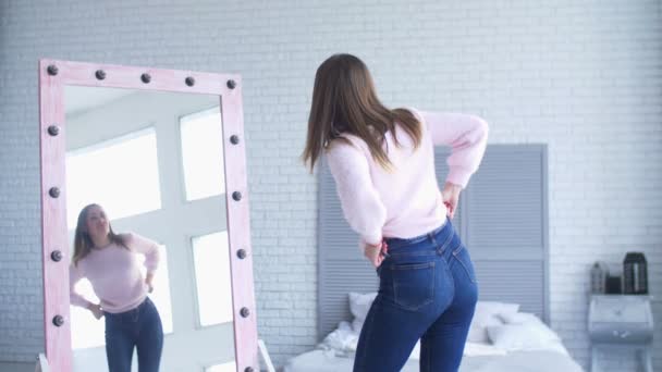 Mooie vrouw probeert te omhoog haar strakke jeans knoop — Stockvideo