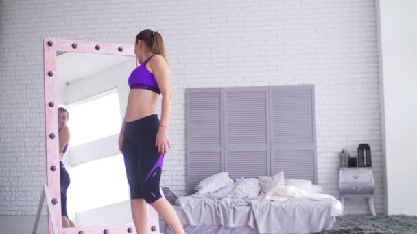 Sportieve vrouw bewonderen van haar lichaamsvorm in spiegel — Stockvideo