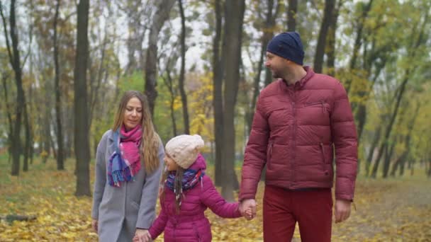 Осенью семья из трех человек наслаждается золотыми листьями — стоковое видео