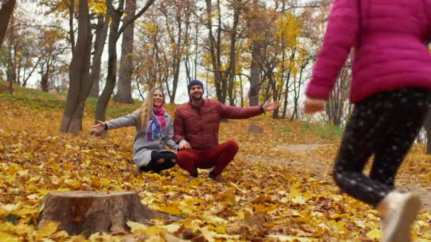 Liebevolle Eltern umarmen kleine Tochter im Herbst — Stockvideo