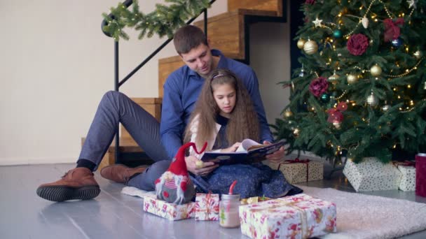 Χαρούμενη οικογένεια ανάγνωση παραμυθιού στο χρόνο Χριστουγέννων — Αρχείο Βίντεο