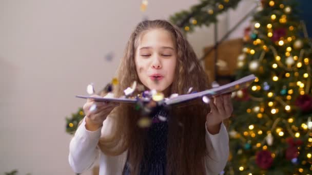 Adorable girl blowing glitter confetti from book — Stock Video