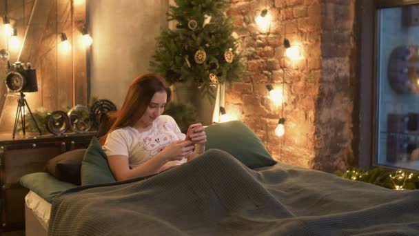 Mulher navegando nas redes sociais no celular na cama — Vídeo de Stock