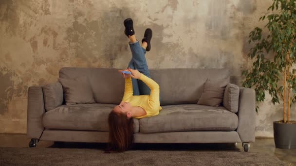 Vrolijke vrouw met cellphone ontspannen op de sofa — Stockvideo