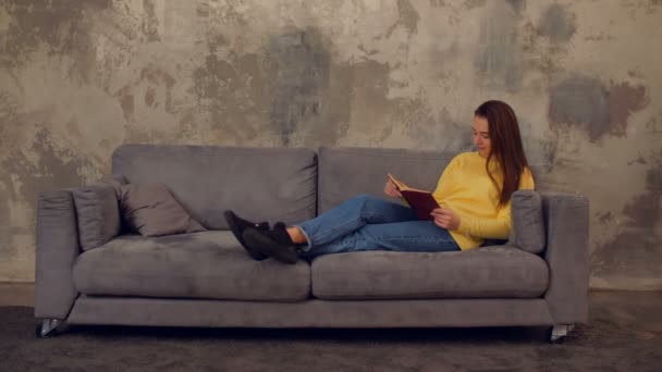 Πολύ κουρασμένος κορίτσι με βιβλίο λαμβάνοντας έναν υπνάκο στον καναπέ — Αρχείο Βίντεο