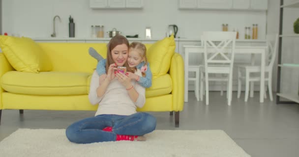 Blije mama en dochter kijken cartoons op telefoon — Stockvideo