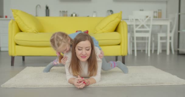 Aufgeregt süße Mädchen huckepack Mama auf dem Fußboden — Stockvideo