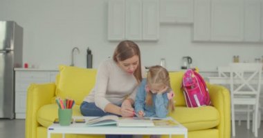 Anne, kızına ev ödevinde yardım ediyor.