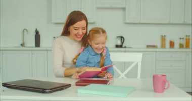 Kaygısız anne ve kızı mutfakta kitap okumak