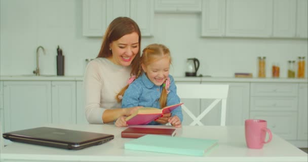 Kaygısız anne ve kızı mutfakta kitap okumak — Stok video