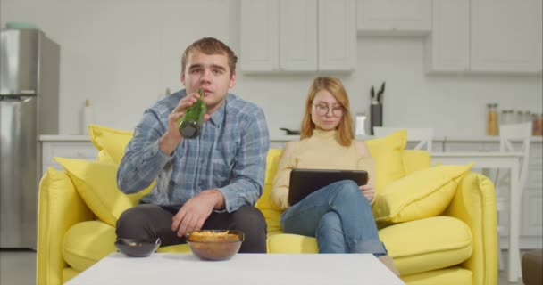 Junges Paar schaut zu Hause auf dem Sofa Sportfernsehen — Stockvideo
