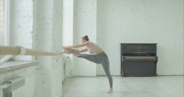 Elegant girl doing leg stretching exercise at barre — Stock Video