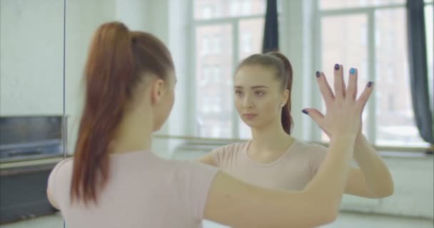 Женщина трогает зеркало, глядя на отражение — стоковое видео