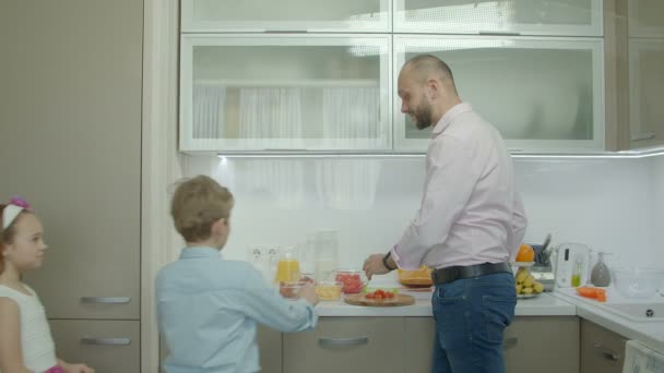 Sonriente padre haciendo el desayuno en la cocina — Vídeo de stock