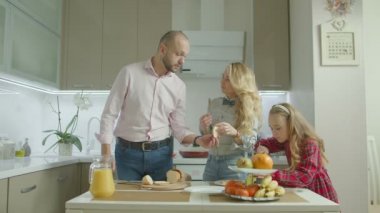 Küçük kız sağlıklı lezzetli breakfast yerli mutfağında sabah yapma kaygısız ailesiyle. Pozitif ebeveyn ve sevimli kızı boş zaman birlikte mutfakta yemek yaparken hafta sonu harcama..