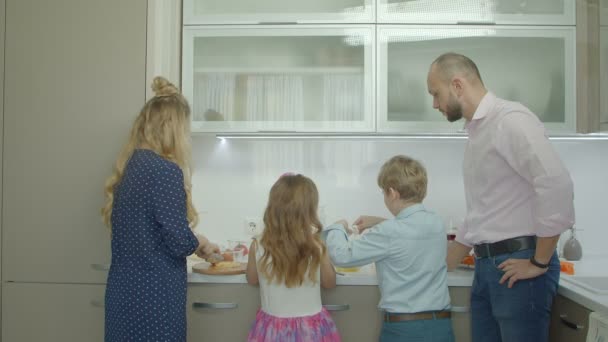 Отец учит братьев и сестер готовить омлет на кухне — стоковое видео