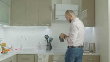 Sabah kahvaltı sırasında yurtiçi mutfakta lezzet çay yapma rahat kıyafetler yakışıklı tek adam. Pozitif adam evde yemek hazırlarken çay yaprakları çaydanlık içine ekleme.