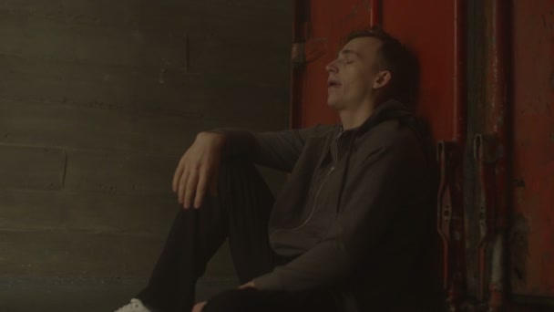 Виснажений перевантажений чоловік у светрі сидить у приміщенні — стокове відео