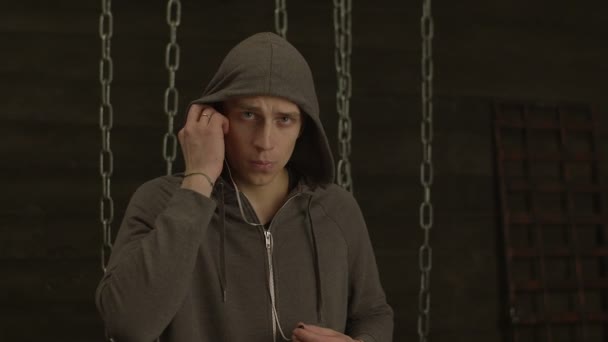 Koncentrovaná muž v hoodie nasadil sluchátka — Stock video