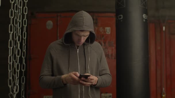 Спортсмен настраивает музыку на мобильное приложение в тренажерном зале — стоковое видео