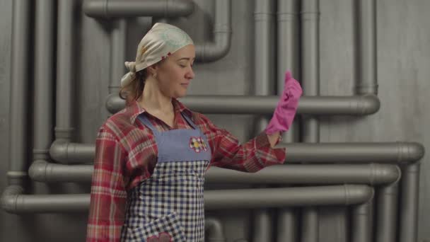 Домохозяйка в резиновых перчатках показывает мышечную силу — стоковое видео
