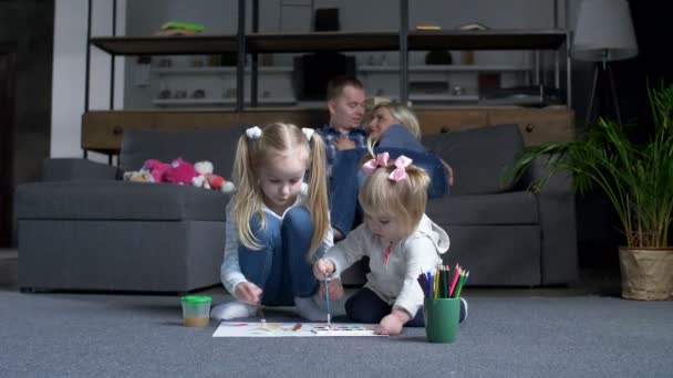 Little girls painting while parents resting on sofa — Stock Video