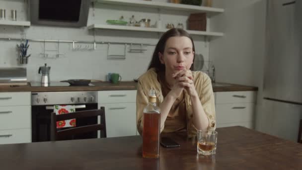 Pensive female sitting in kitchen with alcohol — Stock Video