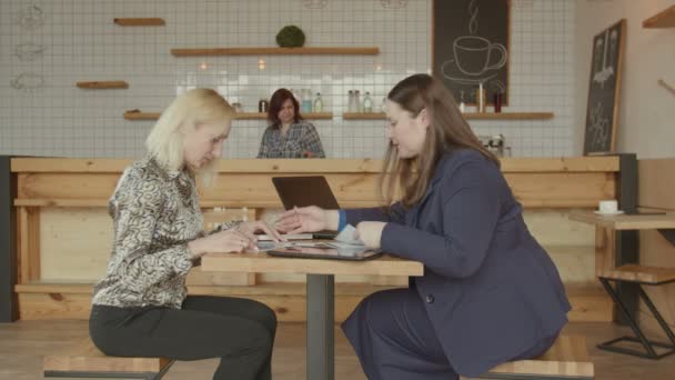 Mujeres con documentos y gadgets trabajando en la cafetería — Vídeo de stock