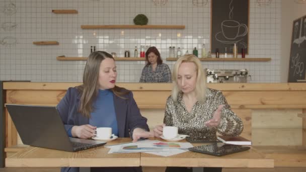 İki kadın kafeterya masasında çalışan kahve içme — Stok video