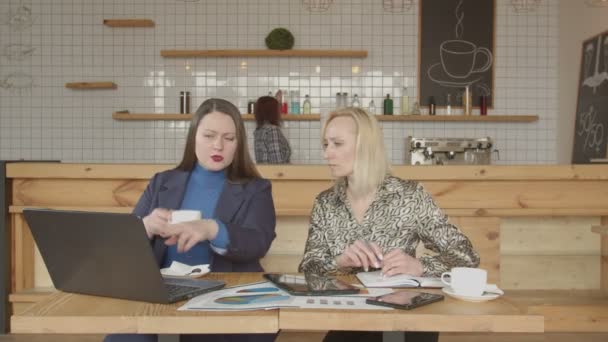 Due donne d'affari in rete con gadget nel caffè — Video Stock