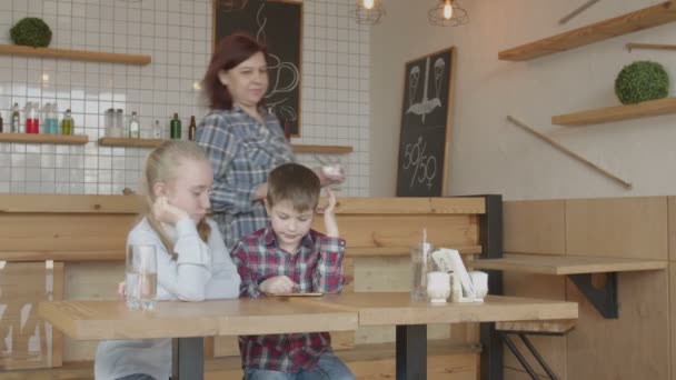 Дети, пользующиеся телефоном, радуются мороженому в кафе — стоковое видео