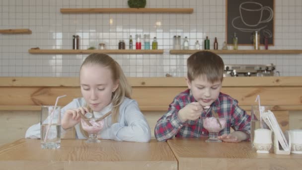 Niños felices comiendo helado con gusto en la cafetería — Vídeo de stock