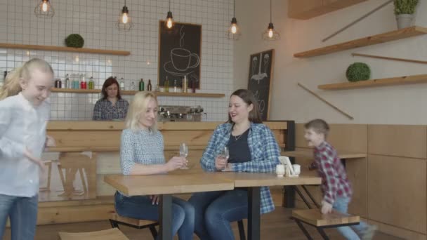Dwie dorosłe matki z dziećmi spotkanie w kawiarni — Wideo stockowe