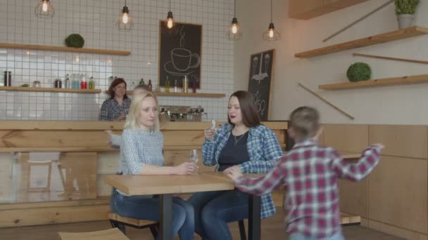 Two single moms with preteen kids meeting in cafe — Stock Video