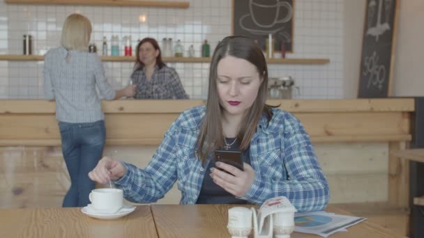 Terfokus freelancer wanita bekerja di telepon di kafe — Stok Video