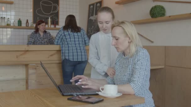 青春期前的女孩撕毁忙碌的妈妈在咖啡馆里的笔记本电脑 — 图库视频影像