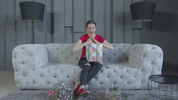 Радостная женщина разворачивает подарочную коробку на день рождения дома — стоковое видео