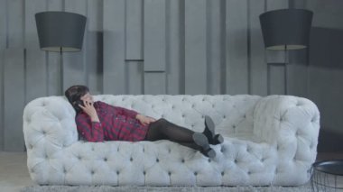 Sıkılmış kadın evde kanepede yatan telefonda konuşurken