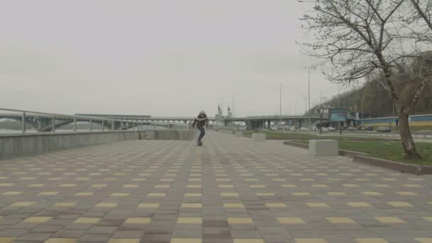 Teenage pojke ridning skateboard ner trottoaren i staden — Stockvideo