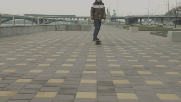 Teenager-Hipster fährt Skateboard und bleibt stehen — Stockvideo