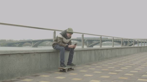 Adolescente skater ouvir música no telefone ao ar livre — Vídeo de Stock